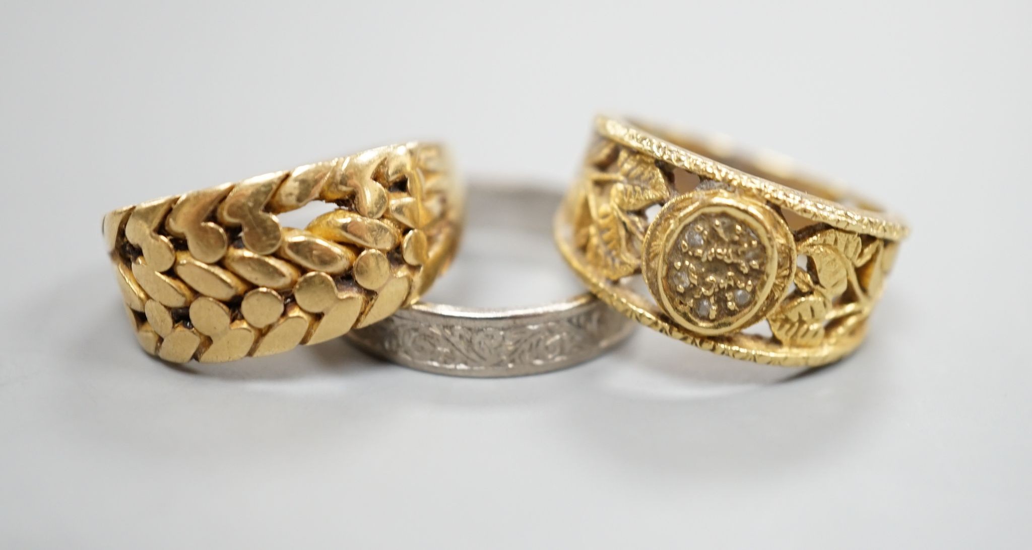 An engraved 18ct white gold wedding band, size P, and 18ct gold interwoven ring(a.f.) and a pierced yellow metal and diamond cluster ring